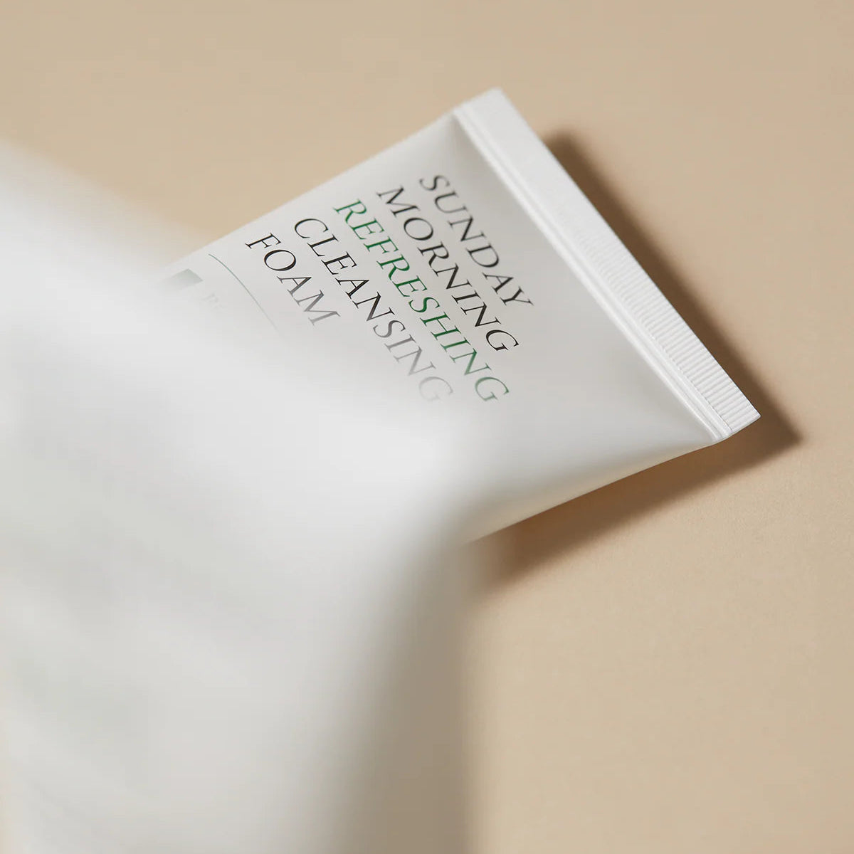 Cleansing foam packaging with text on a beige background