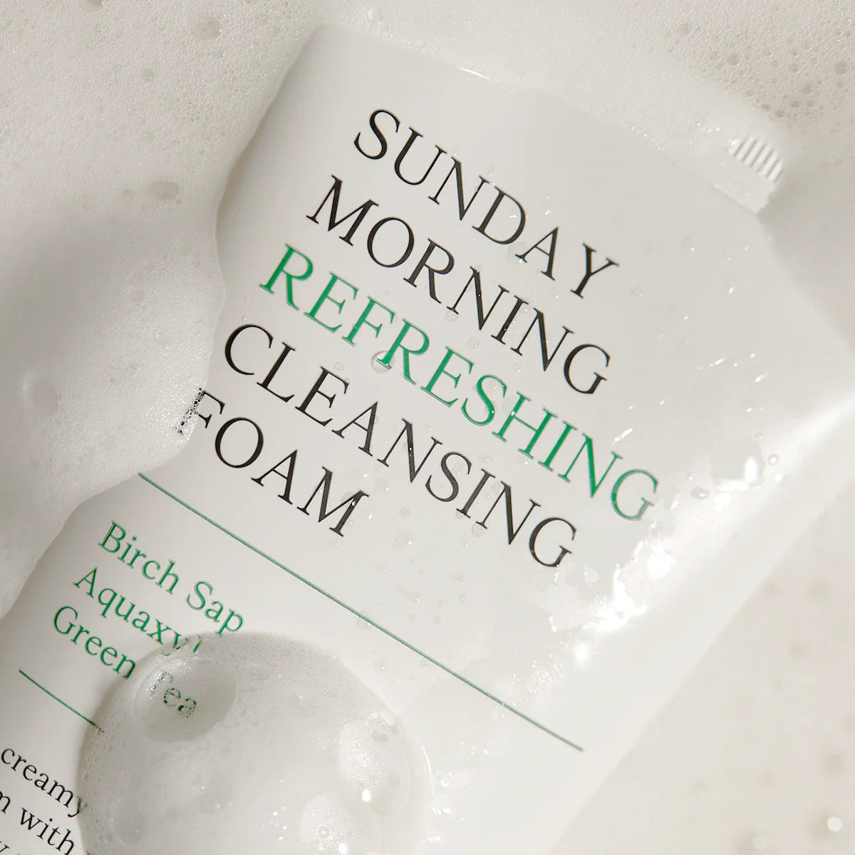 Product packaging for 'Sunday Morning Refreshing Cleansing Foam' on a marble surface.